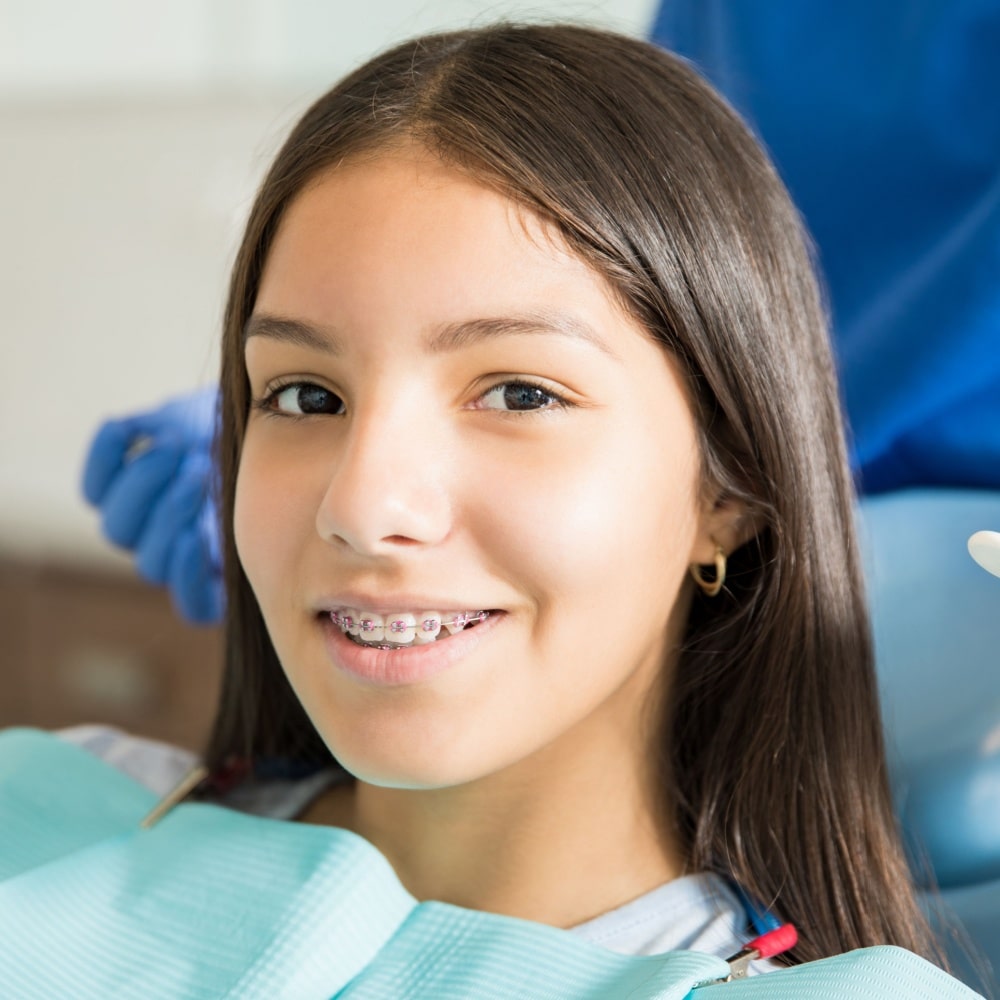 Smiling teenage girl with braces in the dental chair