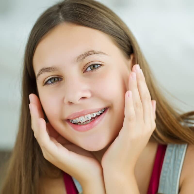 Smiling girl with braces resting her face in her hands