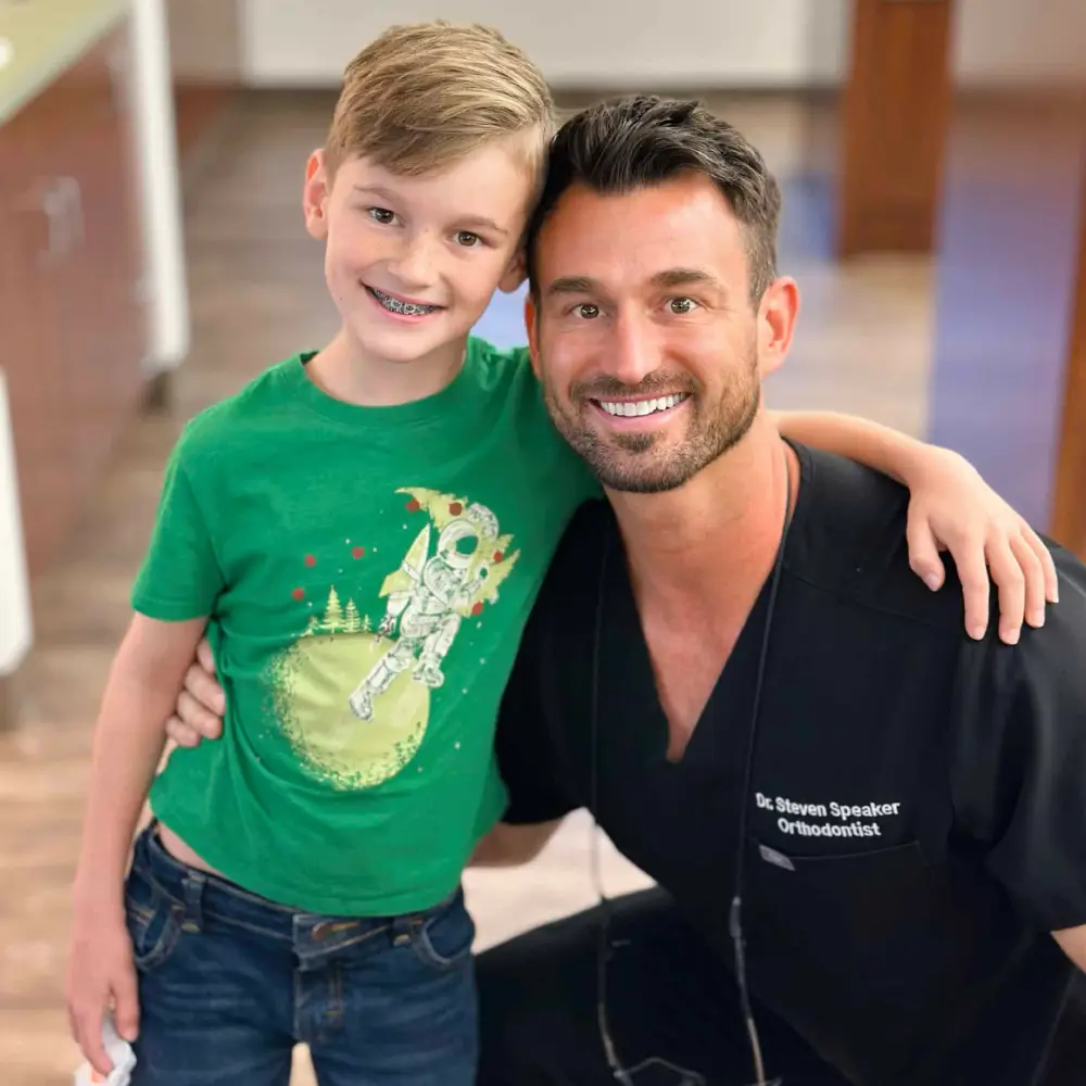 Dr. Steven Speaker with his arm around a smiling young patient